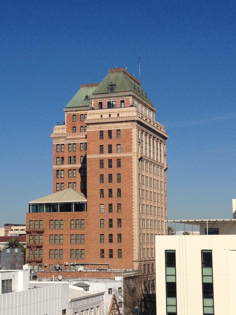 A red brick tower with an ornate green roof against a deep blue sky.